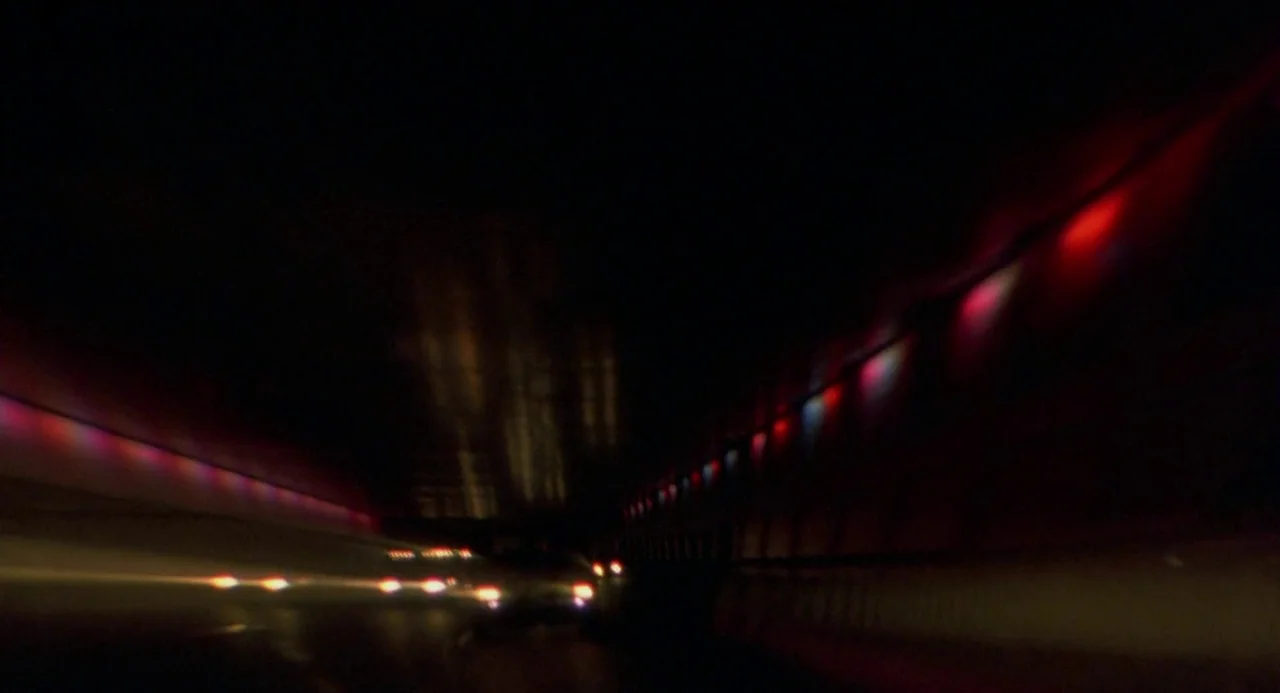Three Colours: Blue (1993) movie still: wide — A dark tunnel interior features blurred streaks of vehicle lights against shadowed concrete walls.…