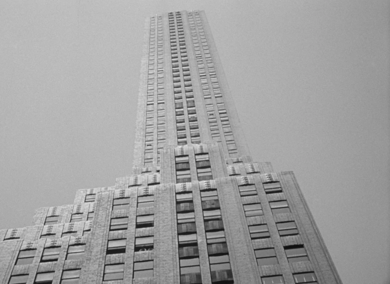 Dance, Girl, Dance (1940) movie still: establishing — A low-angle view of a tall Art Deco skyscraper rising into the sky. Rows of rectangular…