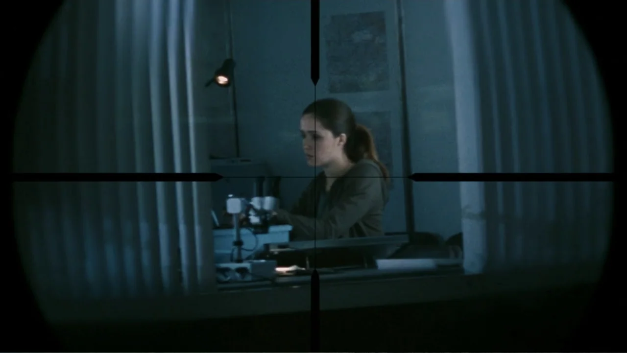 28 Weeks Later (2007) movie still: medium — A dimly lit room contains laboratory equipment including a microscope and a computer monitor. A woman…
