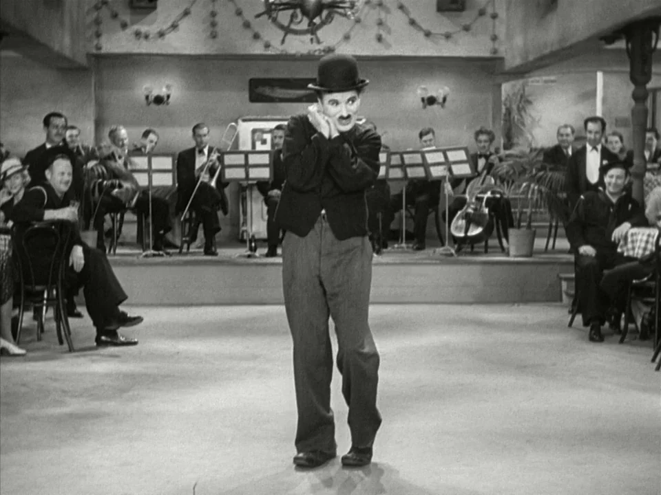 Modern Times (1936) movie still: fullbody — A restaurant interior features a central floor area with a live band performing behind. Charlie Chaplin…