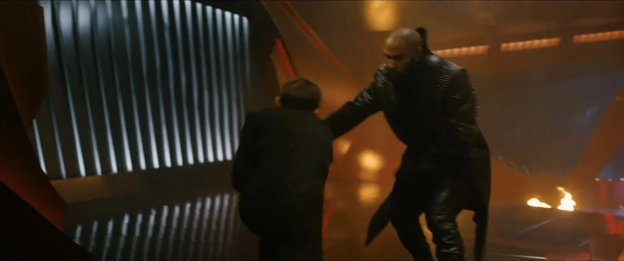 Star Trek: Section 31 (2025) movie still: medium — A dark futuristic interior with metallic wall panels and warm ambient fire light. A man in a dark…