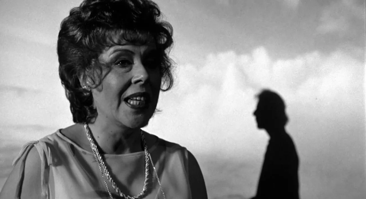Stardust Memories (1980) movie still: medium — An outdoor setting with a bright overcast sky and a prominent sharp silhouette behind. A woman looks…