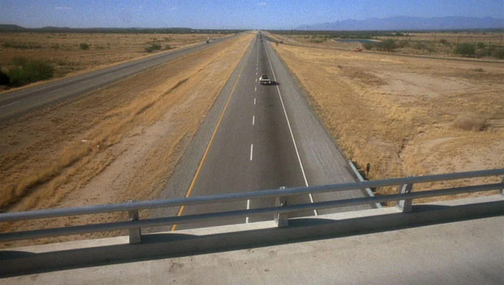Alice Doesn’t Live Here Anymore (1974) movie still: establishing — A long, straight stretch of highway cuts through a vast, arid desert landscape. A…