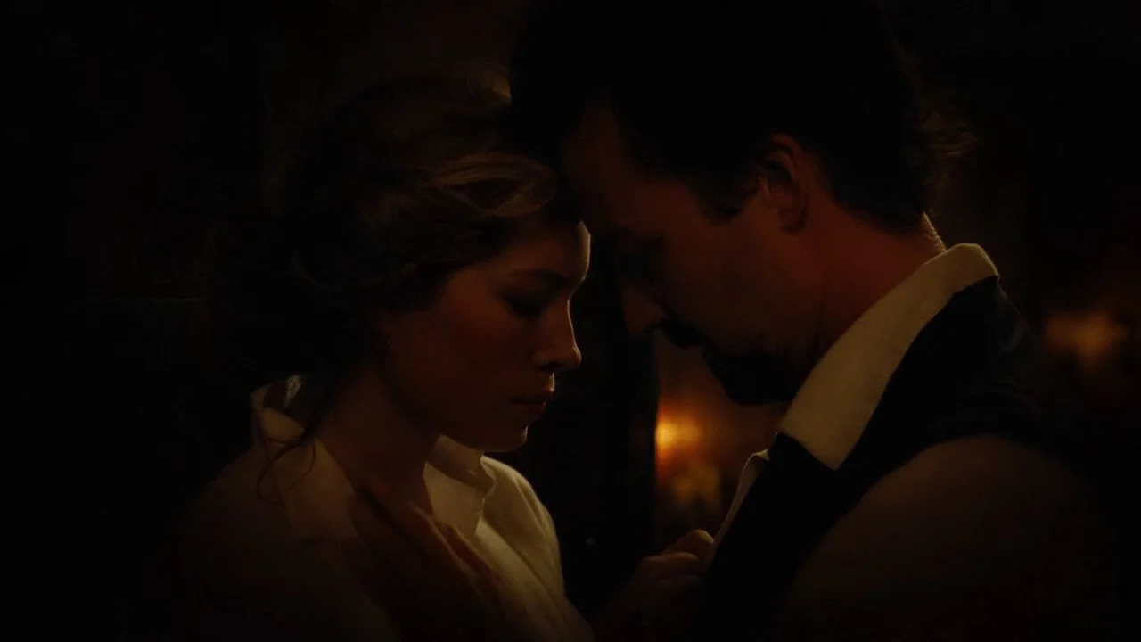 The Illusionist (2006) movie still: medium — A dimly lit, shadowed room provides a setting for two figures in close proximity. A man and woman stand…