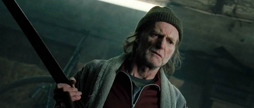 Hot Fuzz (2007) movie still: medium — A dark, cluttered attic space with wooden beams visible in the soft overhead light. An older man in a knit…