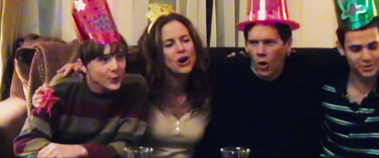 Death Sentence (2007) movie still: medium — Four people sit side-by-side on a couch wearing celebratory party hats. They appear to be singing or…