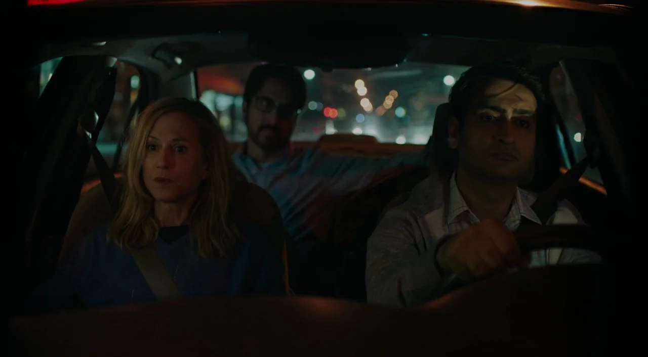 The Big Sick (2017) movie still: medium — The interior of a moving car at night shows three occupants traveling together. A driver steers while two…