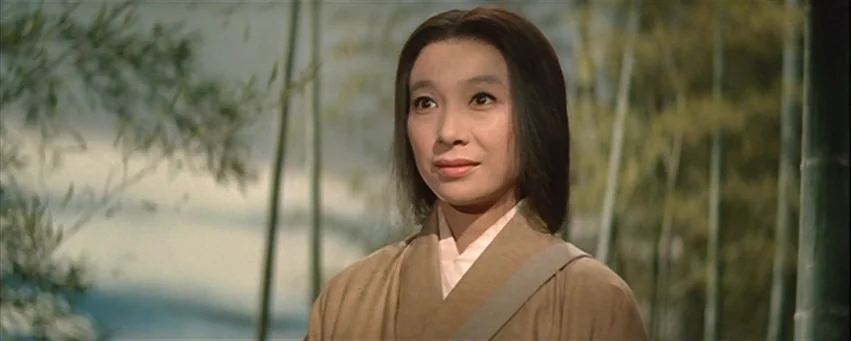 Kwaidan (1964) movie still: closeup — A woman stands in a dense bamboo grove with green stalks surrounding her. She gazes slightly off-camera while…