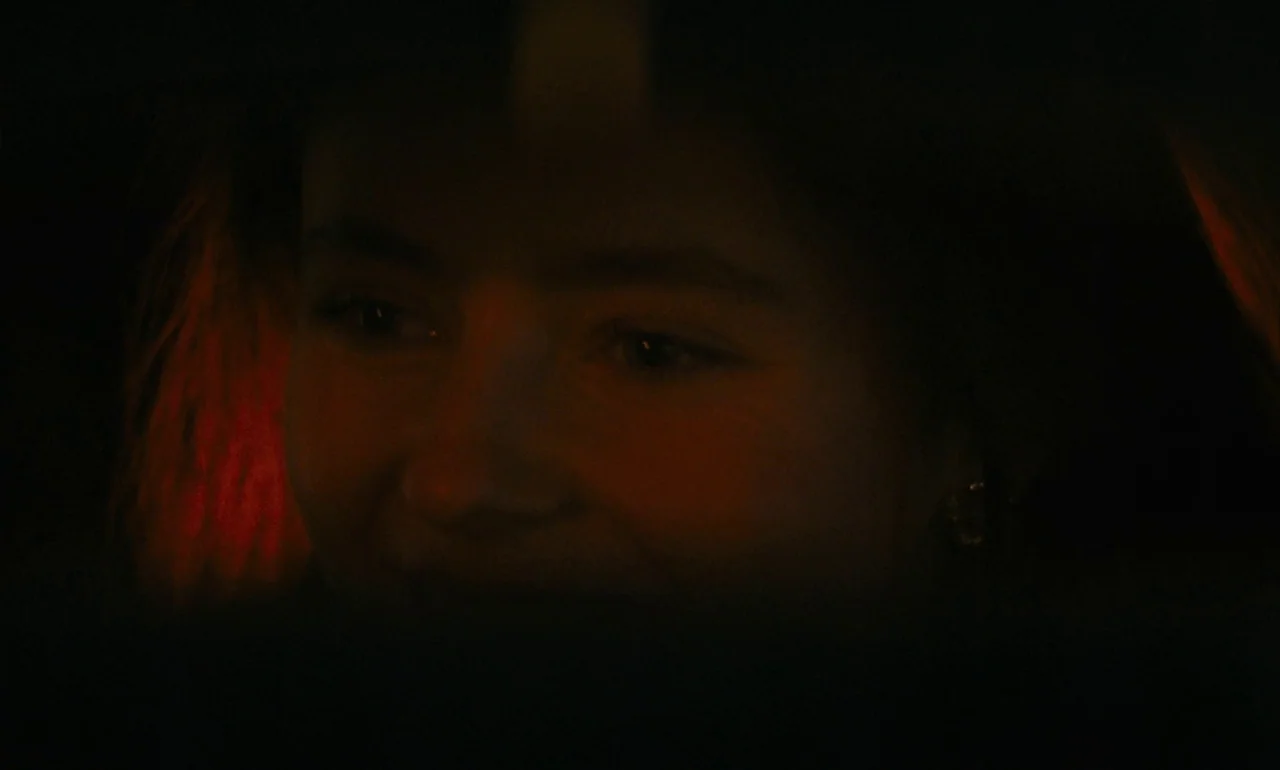 Eileen (2023) movie still: closeup — A dark car interior at night with minimal illumination on the person's face. A woman is seen from the shoulders…