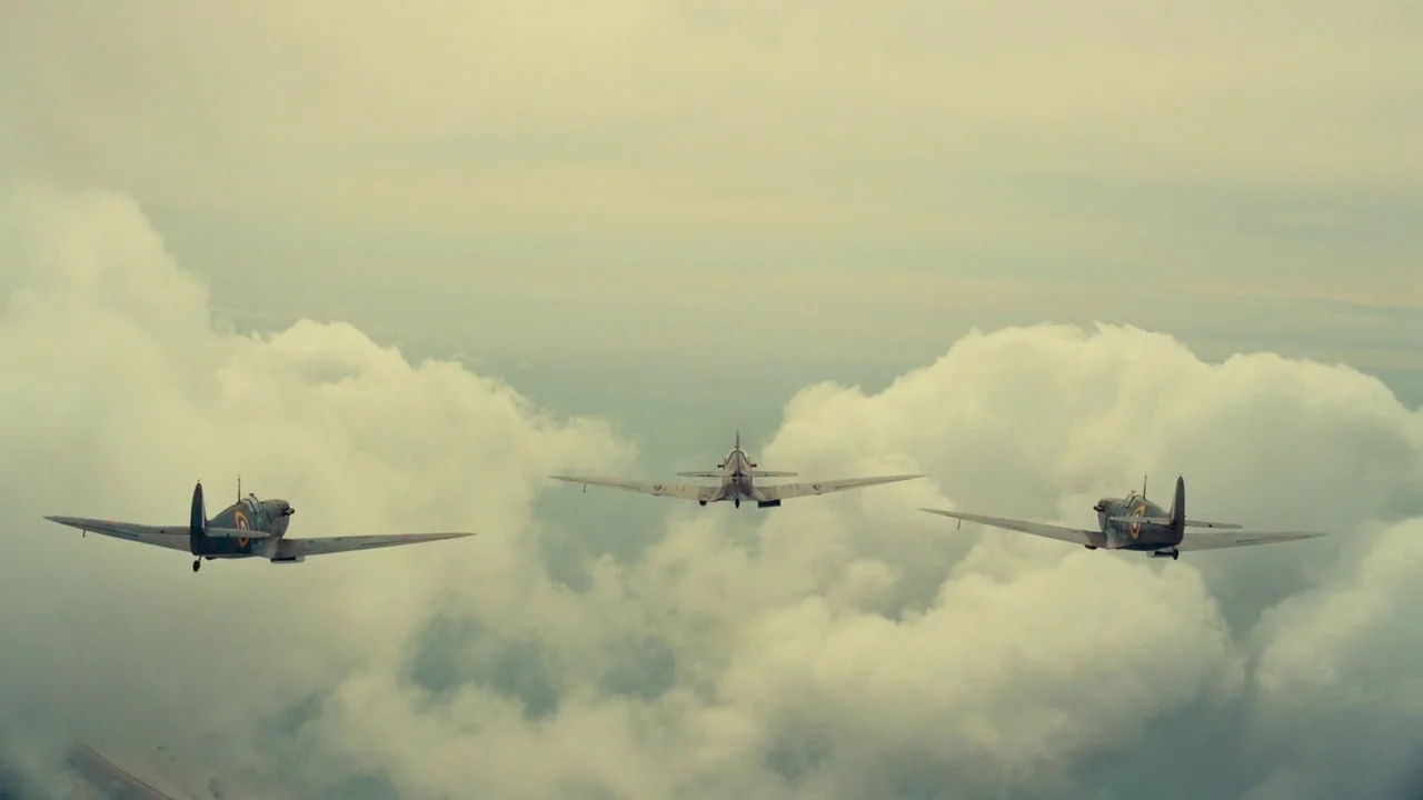 Dunkirk (2017) movie still: wide — Three Supermarine Spitfire aircraft fly in a loose formation above a layer of clouds. The sky is heavily overcast…