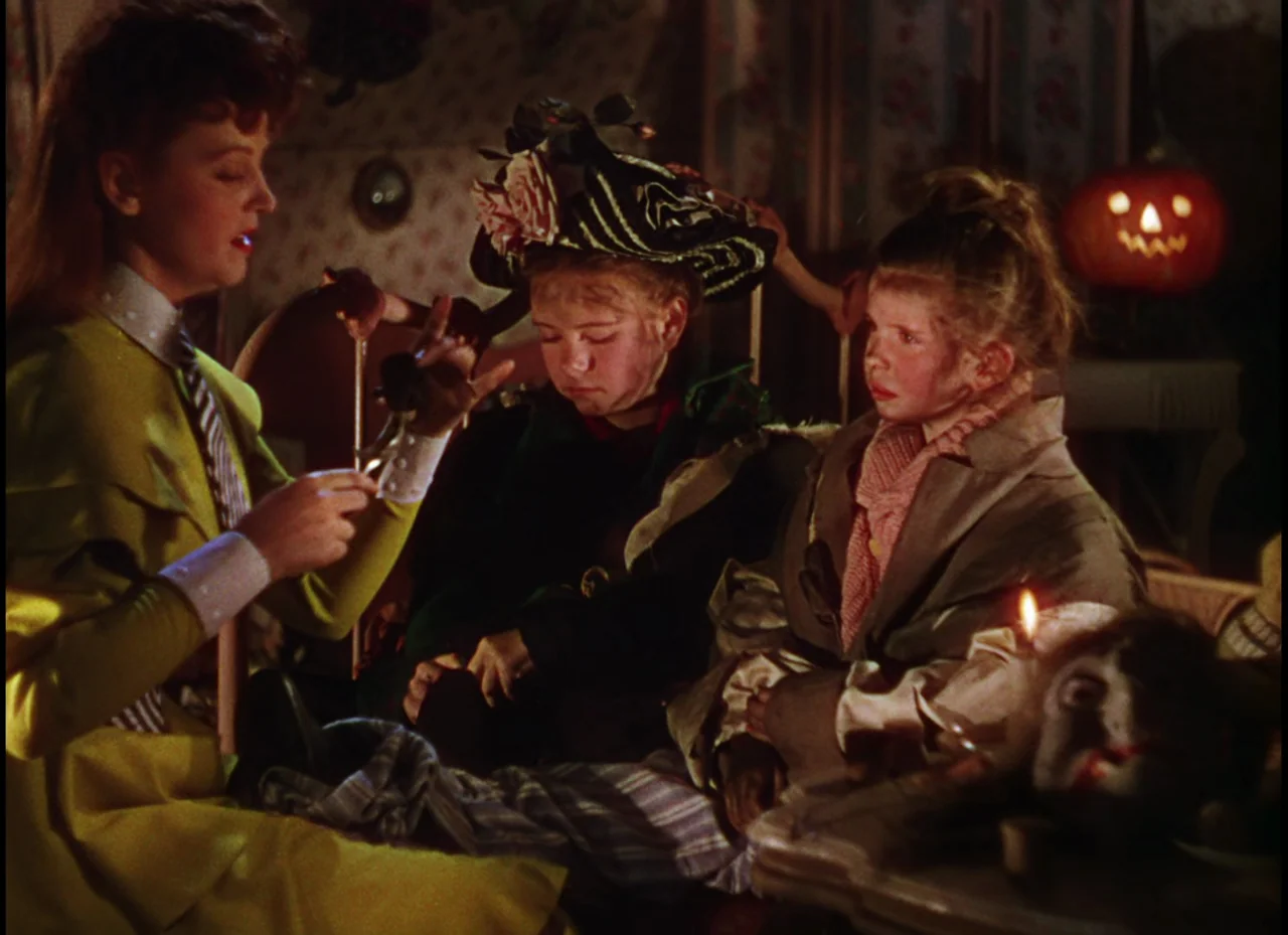 Meet Me In St. Louis (1944) movie still: medium — A dimly lit room features patterned wallpaper and a distant glowing jack-o'-lantern prop. A woman…