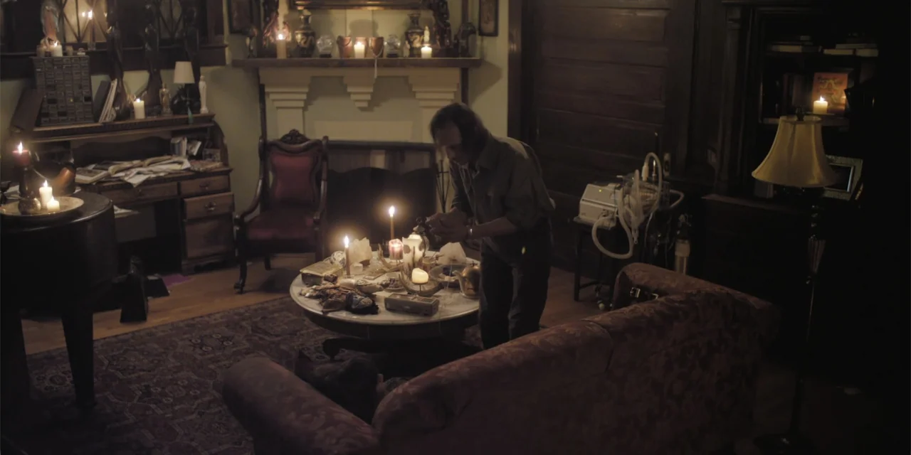 Stalked by My Doctor: A Sleepwalker's Nightmare (2019) movie still: medium — A dimly lit room features a cluttered marble table surrounded by…