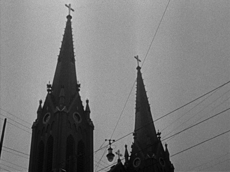 The Big Night (1951) movie still: establishing — Two pointed church steeples with crosses reach up against a grey, overcast sky. Overhead utility…