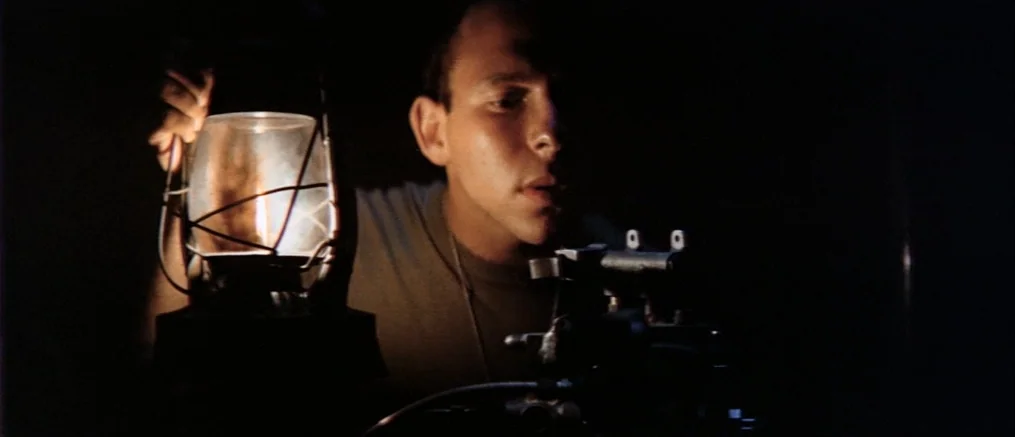 Catch 22 (1970) movie still: medium — A dark, undifferentiated space is illuminated only by a single kerosene lantern. A young man wearing military…