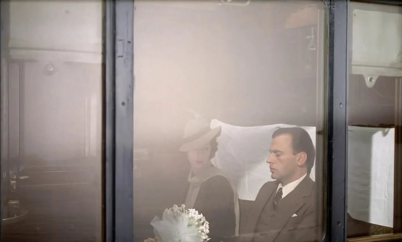 The Conformist (1970) movie still: medium — A 1940s-style train compartment features a window view with slightly blurred, hazy glass. A man and a…