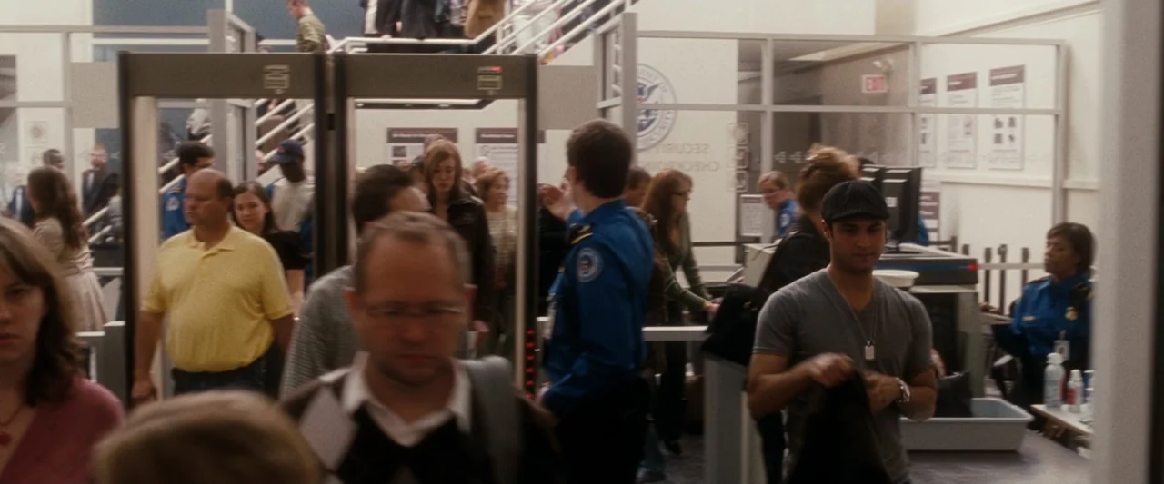 Life As We Know It (2010) movie still: medium — An airport security checkpoint features metal detectors, glass partitions, and signs on walls.…