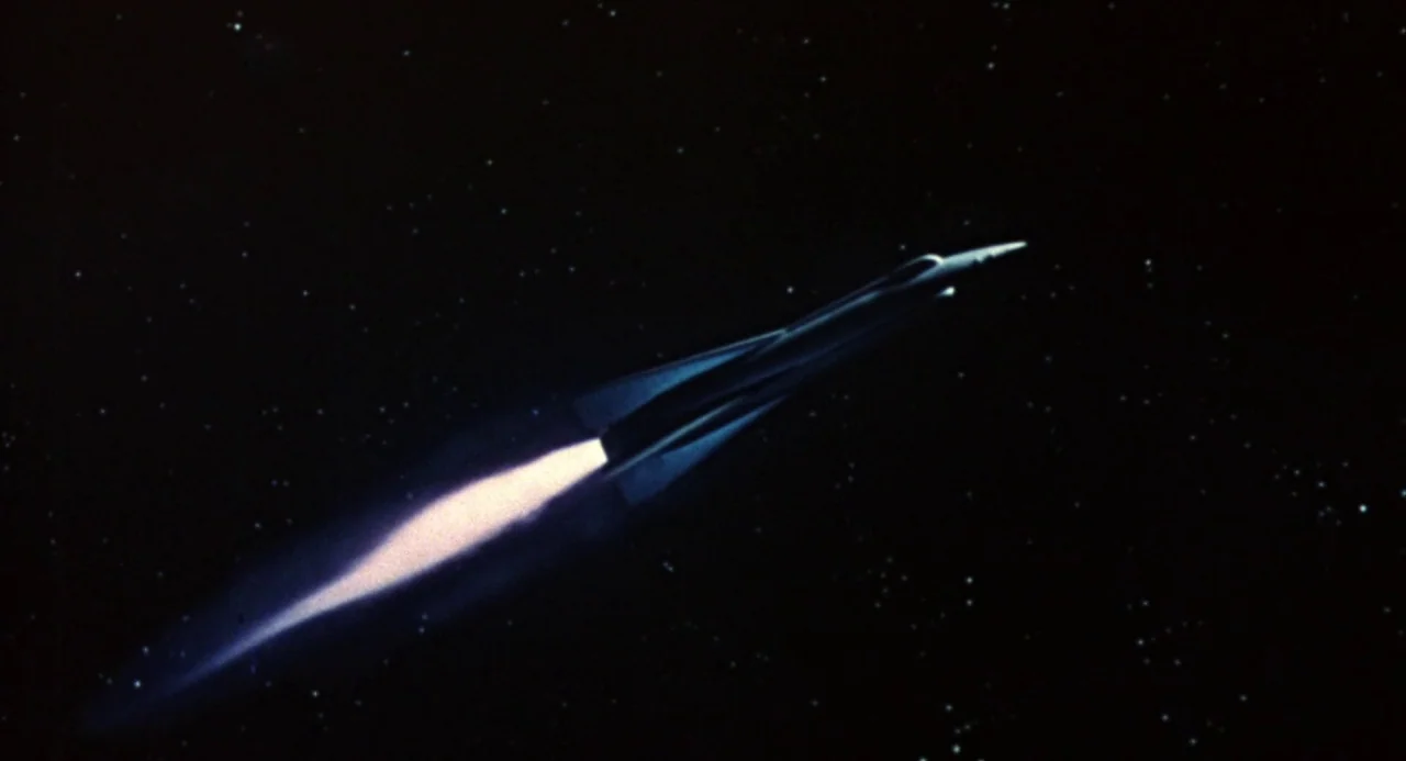 Queen of Blood (1966) movie still: wide — A long, sleek silver rocket flies through the vast, star-filled emptiness of deep space. A bright,…
