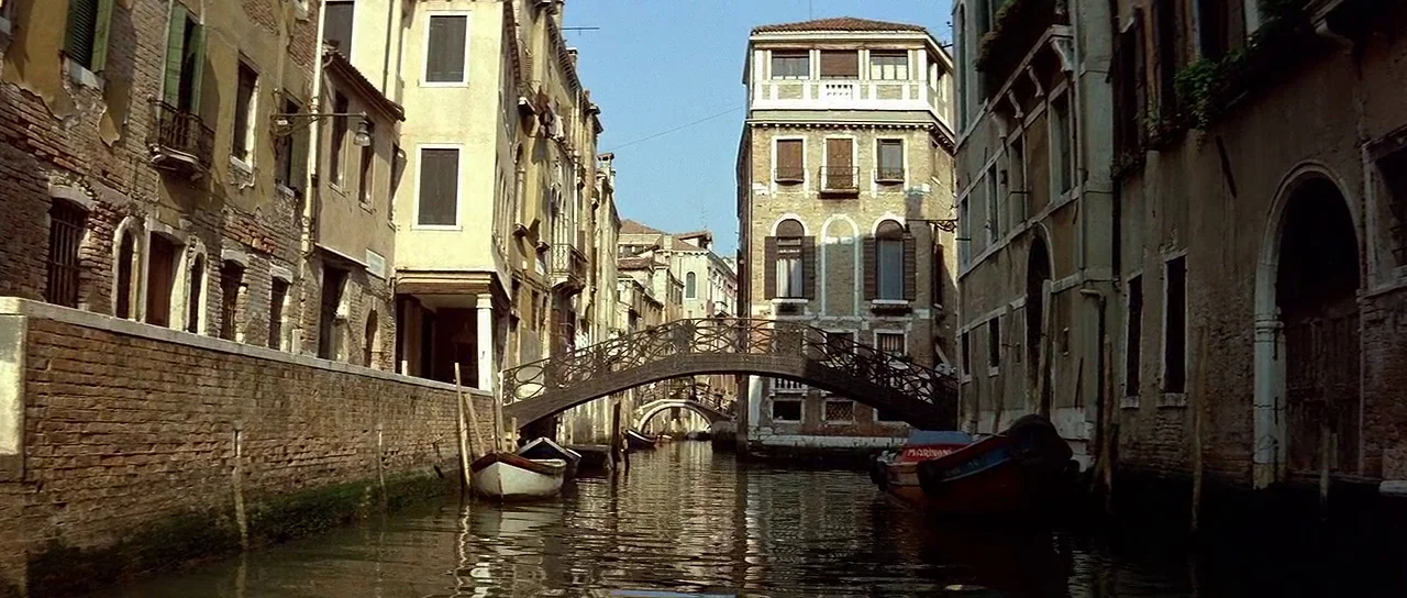 Nikita (1990) movie still: establishing — A narrow canal in Venice is lined with weathered stone and brick apartment buildings. A dark metal…