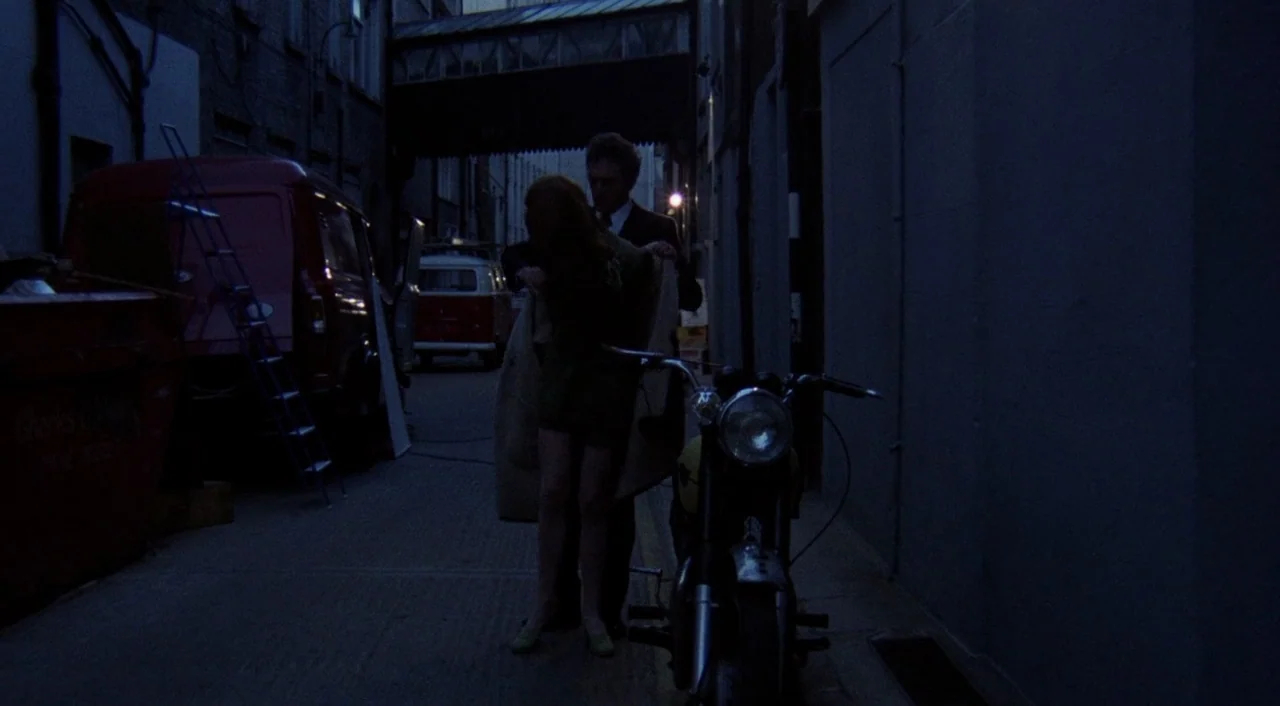 The Iguana with the Tongue of Fire (1971) movie still: fullbody — A dark industrial alley at night contains a parked motorcycle and utility…