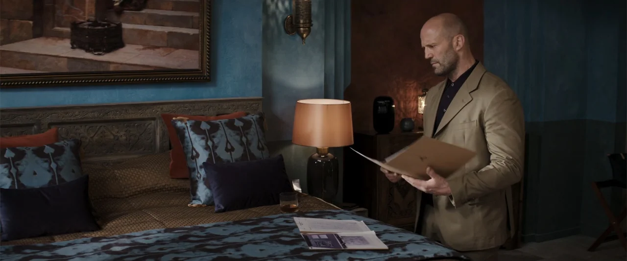 Operation Fortune: Ruse de Guerre (2023) movie still: medium — A hotel suite features blue-toned walls with an ornate bed and a large framed…