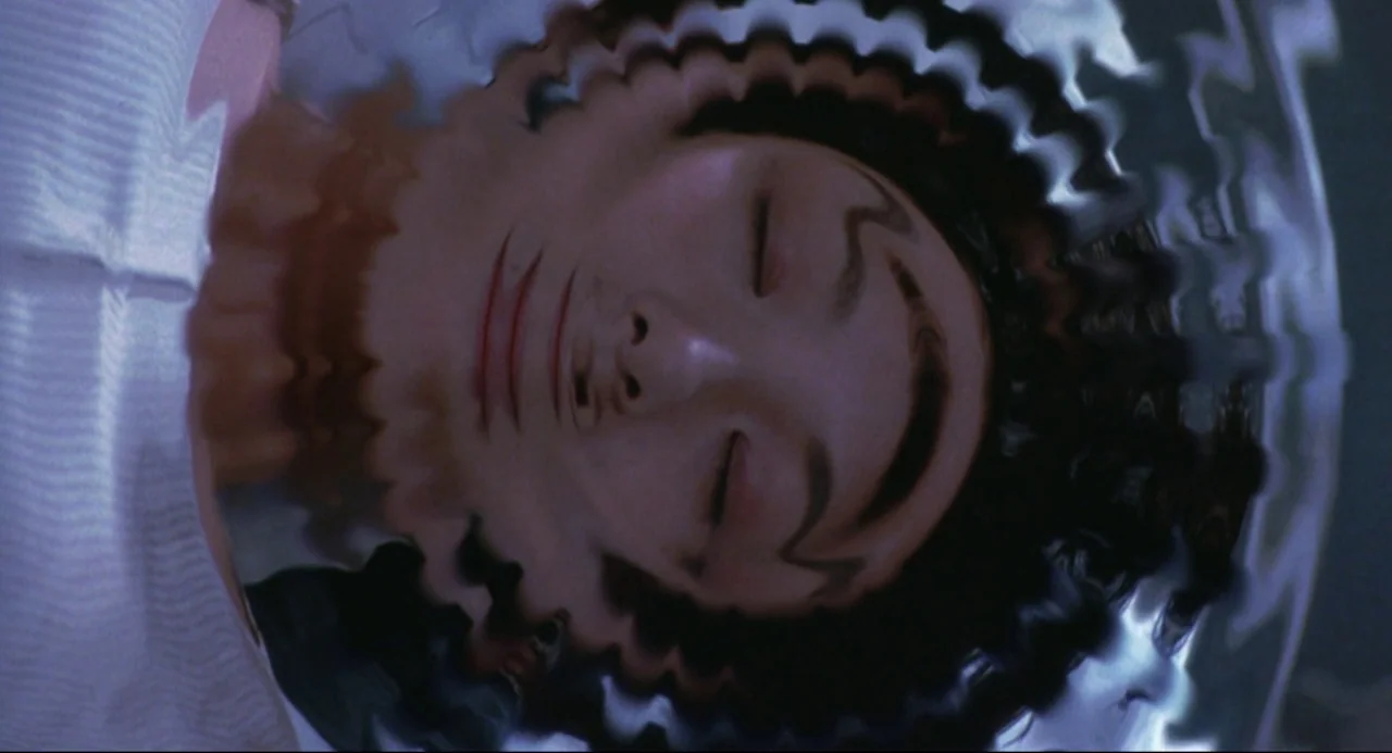Godzilla vs. SpaceGodzilla (1994) movie still: closeup — A close-up view shows a person's face reflected or submerged in rippling water. The…