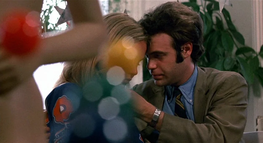 A Safe Place (1971) movie still: medium — A man and woman rest their foreheads together in a brightly lit room. A houseplant sits in the background…