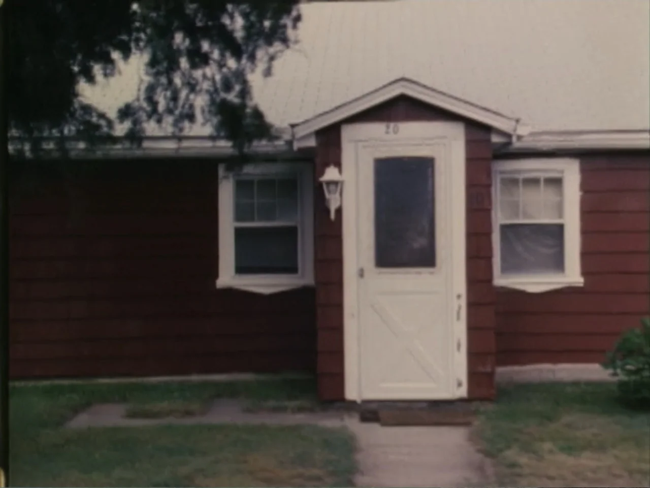 5 American Handguns - 5 American Kids (1995) movie still: establishing — A single-story suburban house features dark red siding and a central white…