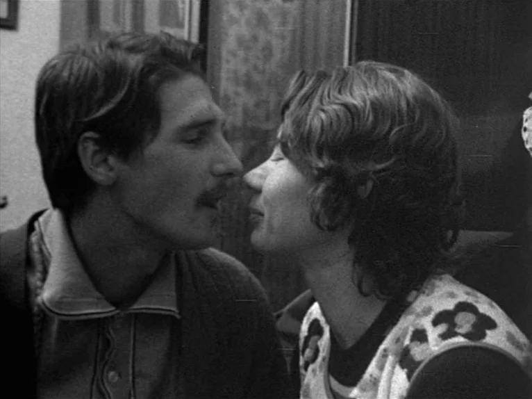 Family Nest (1979) movie still: medium — An indoor setting with simple walls and indistinct background features. A man and a woman stand close,…