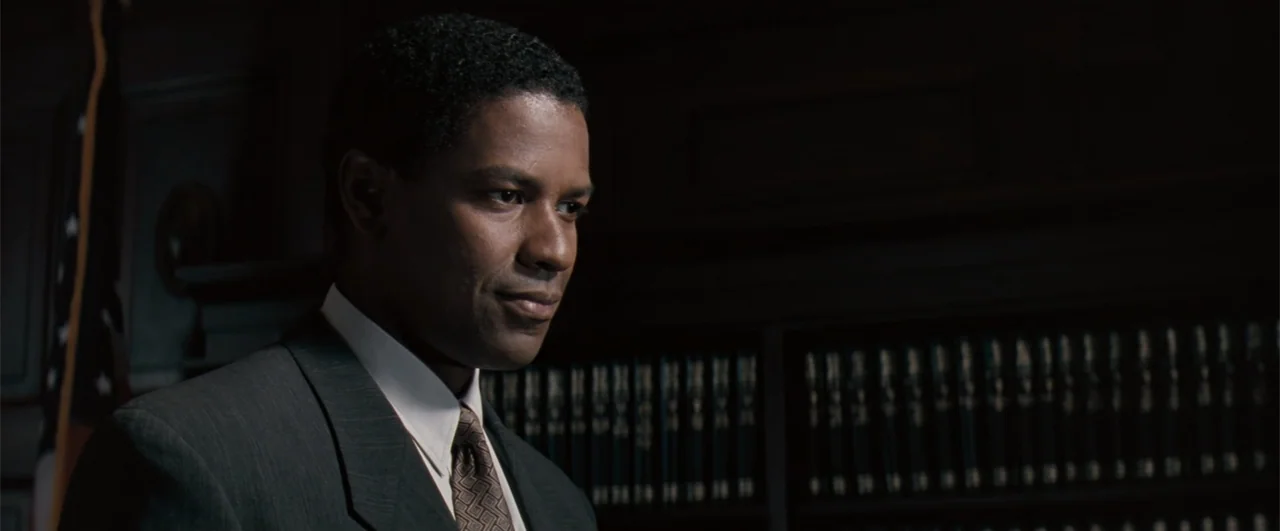 The Pelican Brief (1993) movie still: closeup — A dark law office features rows of bound legal volumes on shelves in the background. A man in a suit…