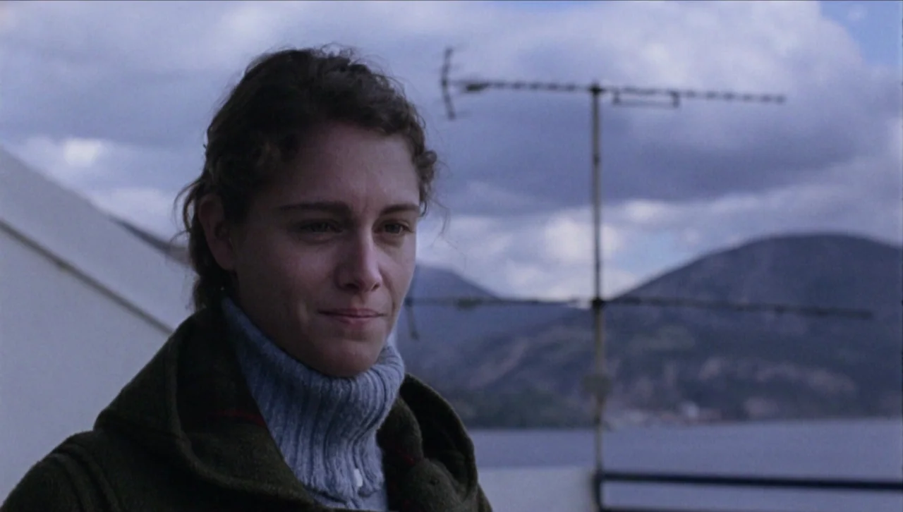 Attenberg (2010) movie still: closeup — A woman stands on a rooftop overlooking a body of water and distant hills. A television antenna stands…