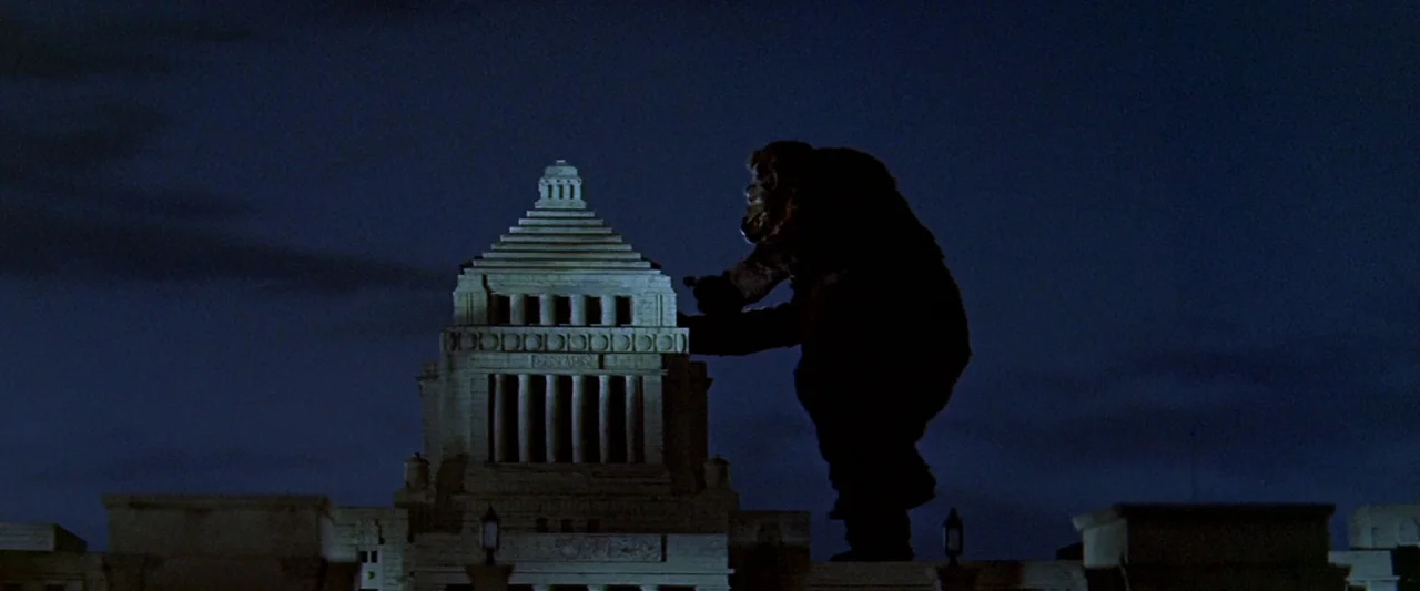 King Kong Vs. Godzilla (1962) movie still: wide — A massive creature looms over the top of the National Diet Building at night. The creature is…