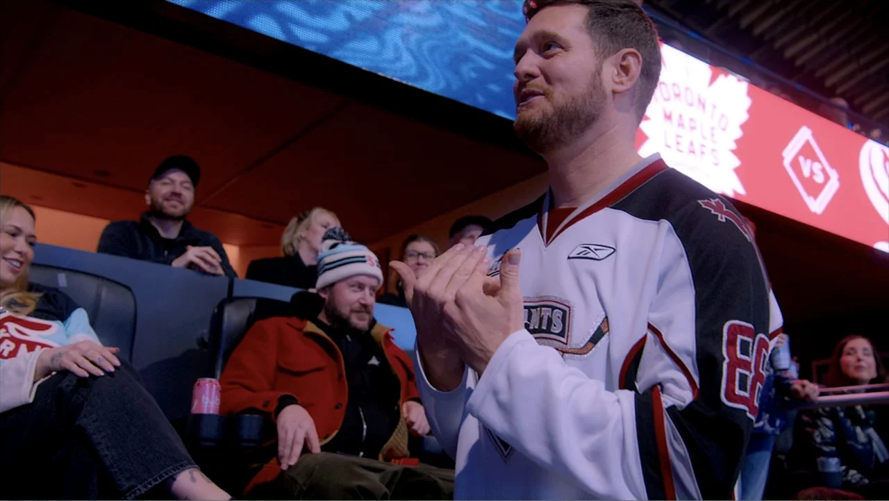 Jack in Time for Christmas (2024) movie still: medium — A crowded professional hockey arena interior is filled with stadium seating and bright…