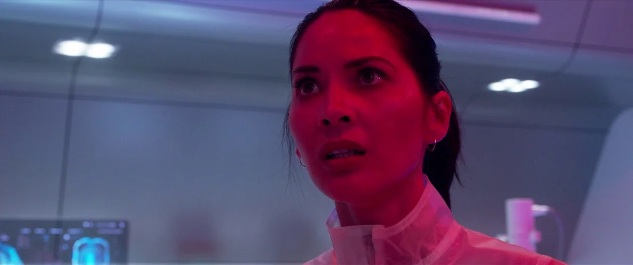 The Predator (2018) movie still: closeup — A sleek, sterile, futuristic interior corridor features white curved walls and glowing data panels. A…