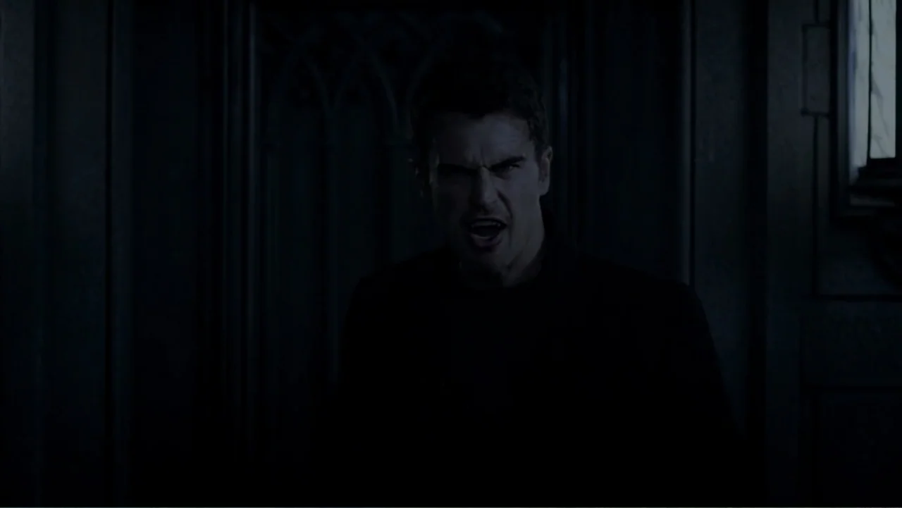 Underworld: Blood Wars (2016) movie still: medium — A dimly lit room with dark paneling behind the central male figure. The man looks directly ahead…