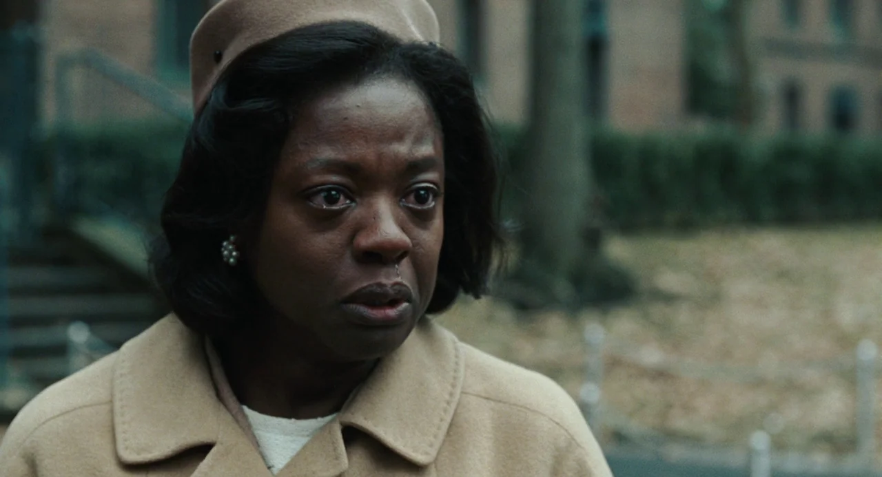 Doubt (2008) movie still: closeup — An outdoor urban environment features a blurry background of trees and brick architecture. A middle-aged woman…