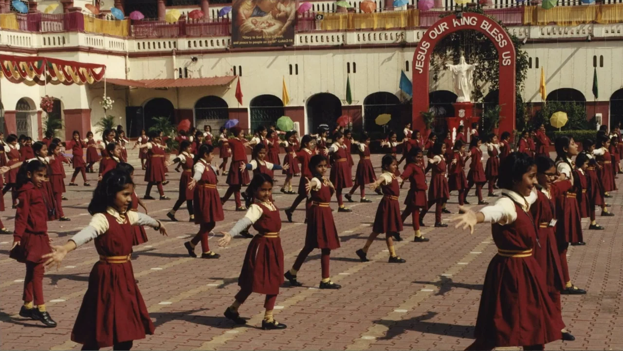 Victoria's Secret: The Tour '23 (2023) movie still: wide — A large outdoor school courtyard is decorated with colorful banners and a religious…
