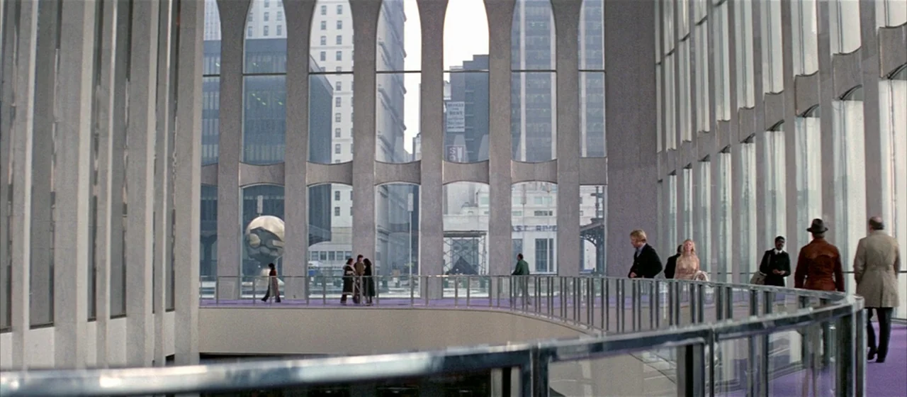 Three Days of the Condor (1975) movie still: wide — A modern multi-story atrium features arched window pillars overlooking an outdoor plaza with a…