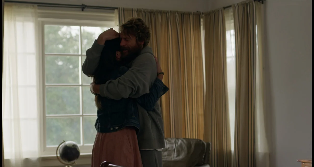 One True Loves (2023) movie still: medium — A residential room featuring a large multi-pane window covered by beige curtains. A man and a woman…