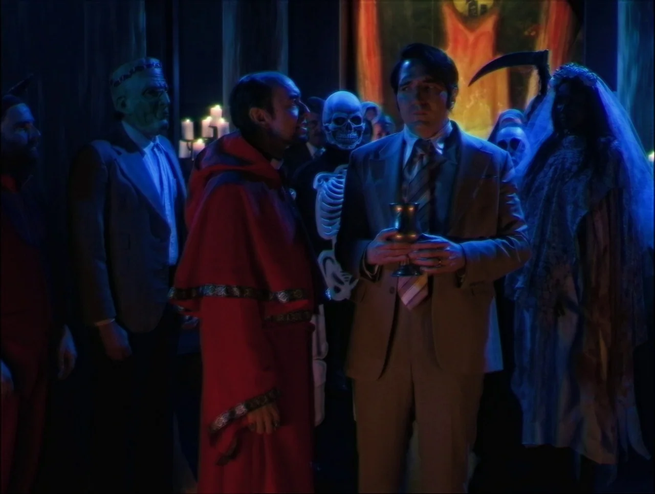 Late Night With The Devil (2023) movie still: medium — An interior space is filled with people wearing varied theatrical costumes and ritual attire.…