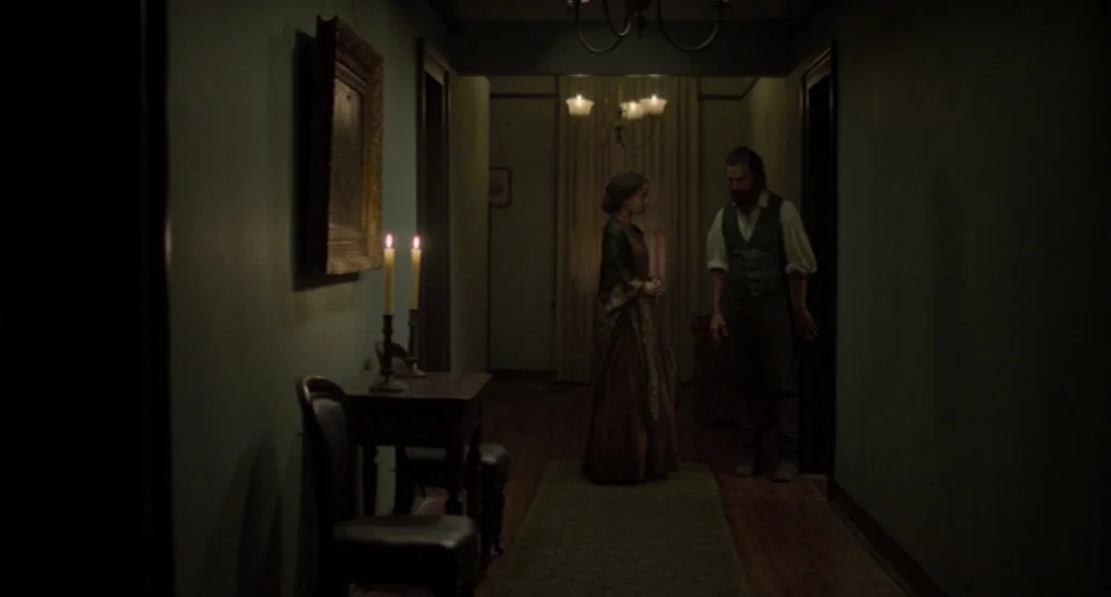 Free State of Jones (2016) movie still: fullbody — A dimly lit 19th-century hallway features teal walls, wooden floors, and framed artwork. A woman…