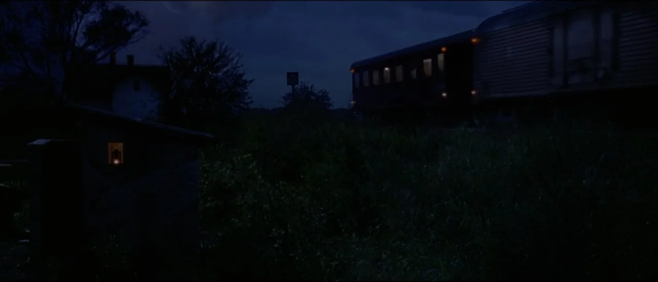 The Peacemaker (1997) movie still: wide — A rural railway track at night is surrounded by tall grass and distant trees. A train carriage sits on the…