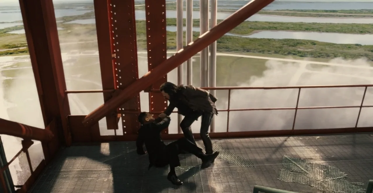 Men in Black 3 (2012) movie still: wide — A high-altitude red steel catwalk sits overlooking a marshy landscape with white steam plumes. One man in…