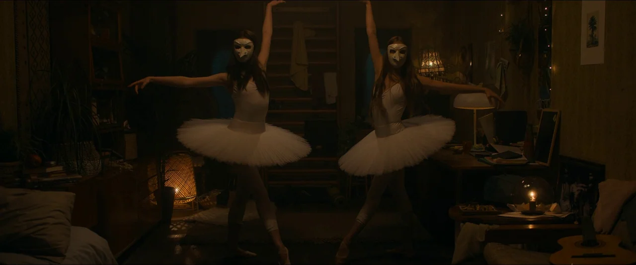 Birds of Paradise (2021) movie still: fullbody — A dimly lit room filled with clutter including wooden furniture and a guitar. Two dancers in white…