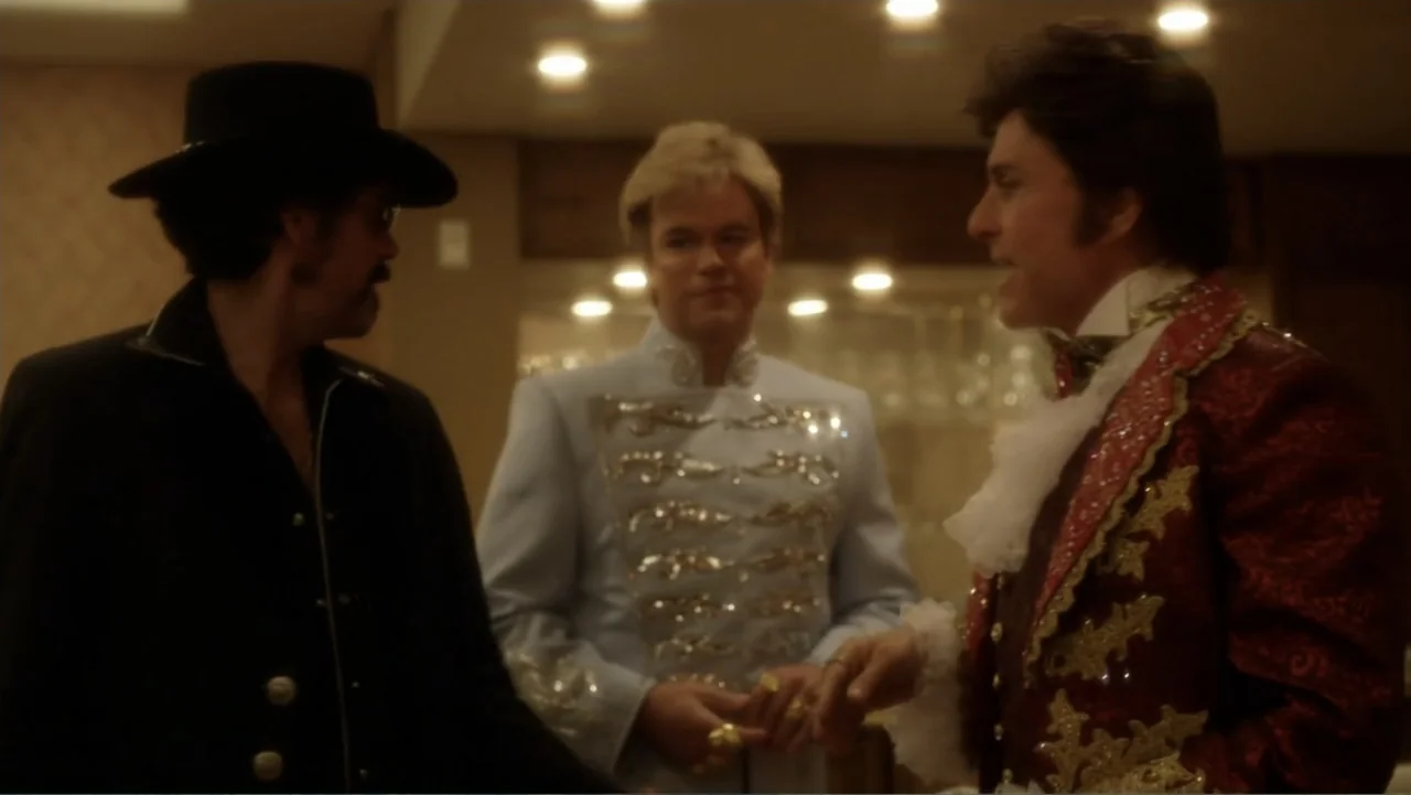 Behind the Candelabra (2013) movie still: medium — A dimly lit lounge setting features three men engaged in conversation near a bar area. The men…