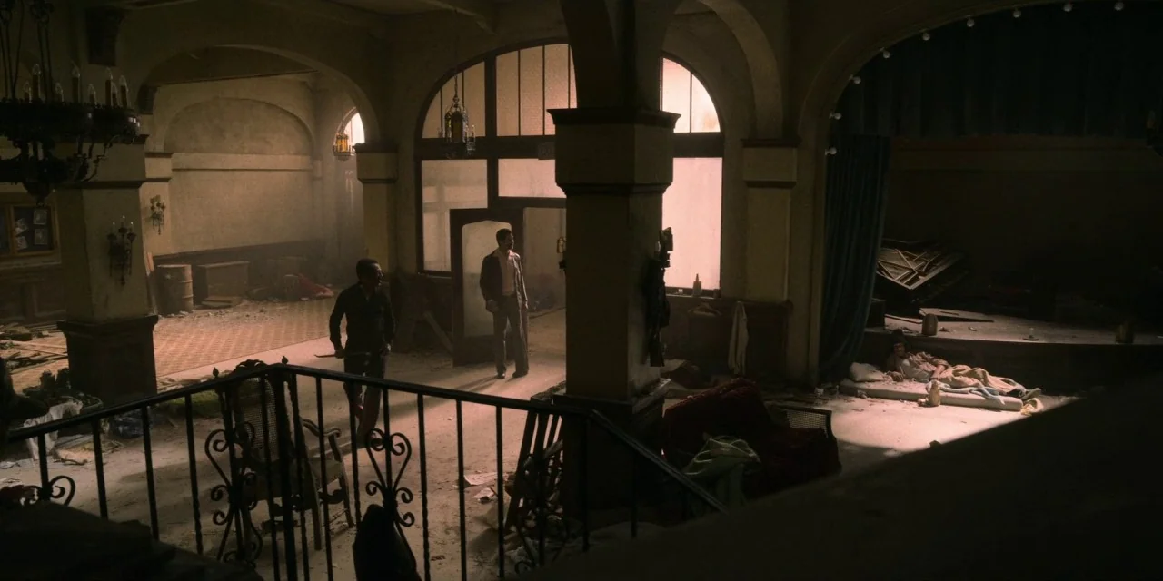 Dolemite Is My Name movie still: wide — A dilapidated, dusty grand interior features arched windows, stone pillars, and debris-strewn floors. Three…