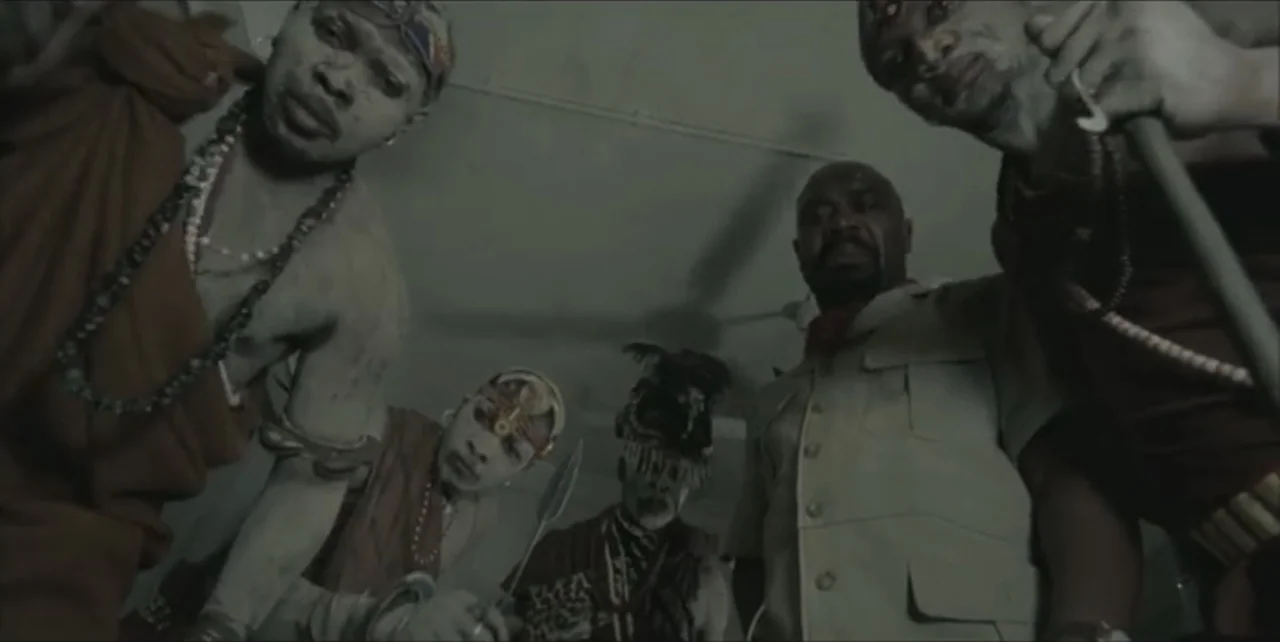 Exorcist: The Beginning (2004) movie still: medium — Five men stand in an indoor space and peer down directly into the lens. They are dressed in a…