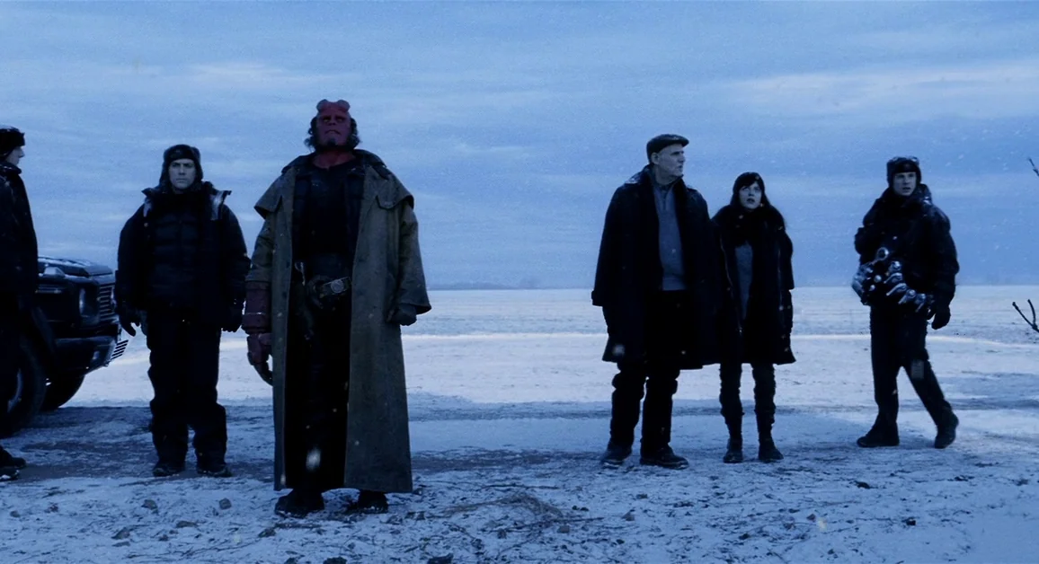 Hellboy (2004) movie still: fullbody — A group of six figures stands along a snowy landscape during a cold winter day. They are arranged in a…