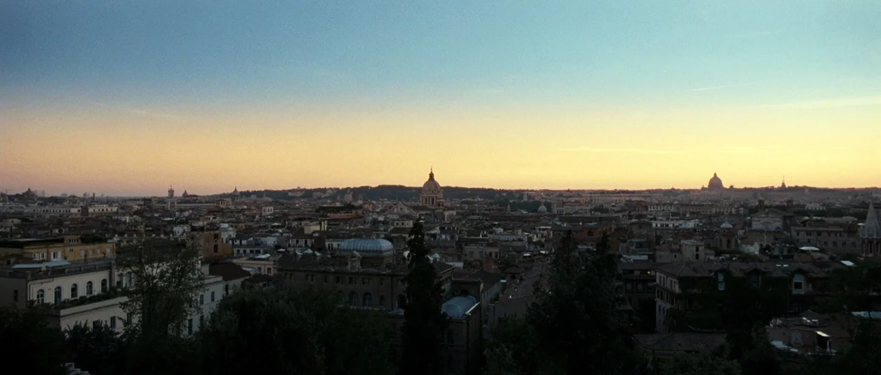 The Great Beauty (2013) movie still: establishing — A panoramic view of the Rome skyline under a soft twilight sky at sunset. Domes, terracotta…