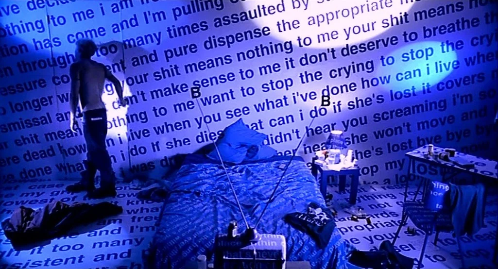 Nowhere (1997) movie still: wide — A room features walls and floors completely covered in black printed text on white. The space is illuminated by a…
