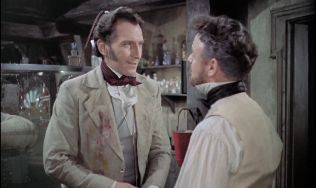 The Curse of Frankenstein (1957) movie still: medium — A cluttered laboratory with wooden beams and various glass bottles in the background. Two men…